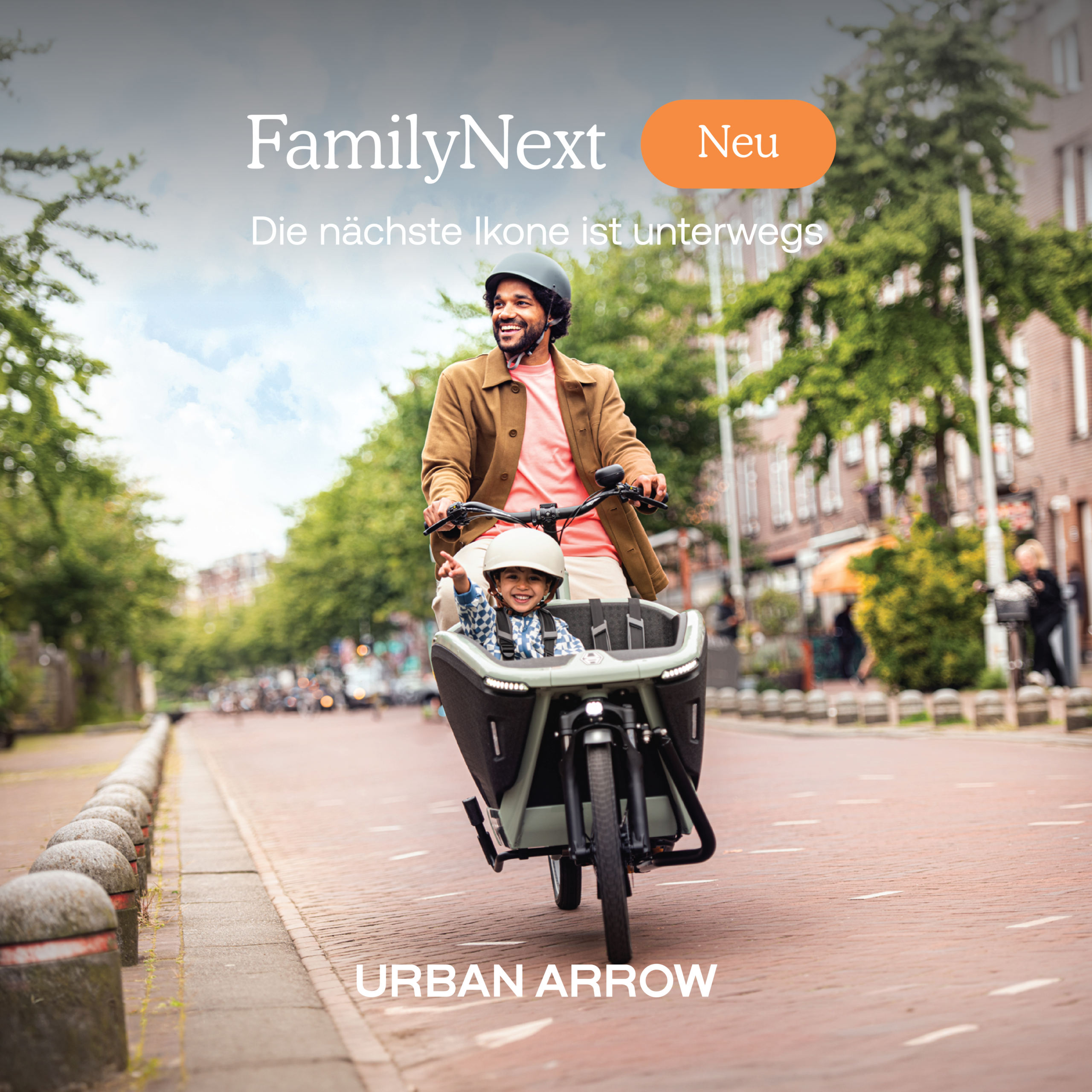 FamilyNext_Lifestyle_DE1 - mycargobike köln GmbH Man on a cargo bike smiling with a child in the front seat, riding through a city street, 'URBAN ARROW' branding visible.