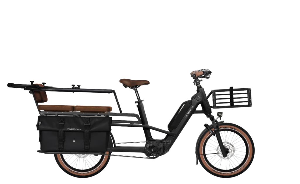 Black electric cargo bike with front basket, rear pannier bags, and brown saddle; designed for carrying cargo on a long-tail frame.